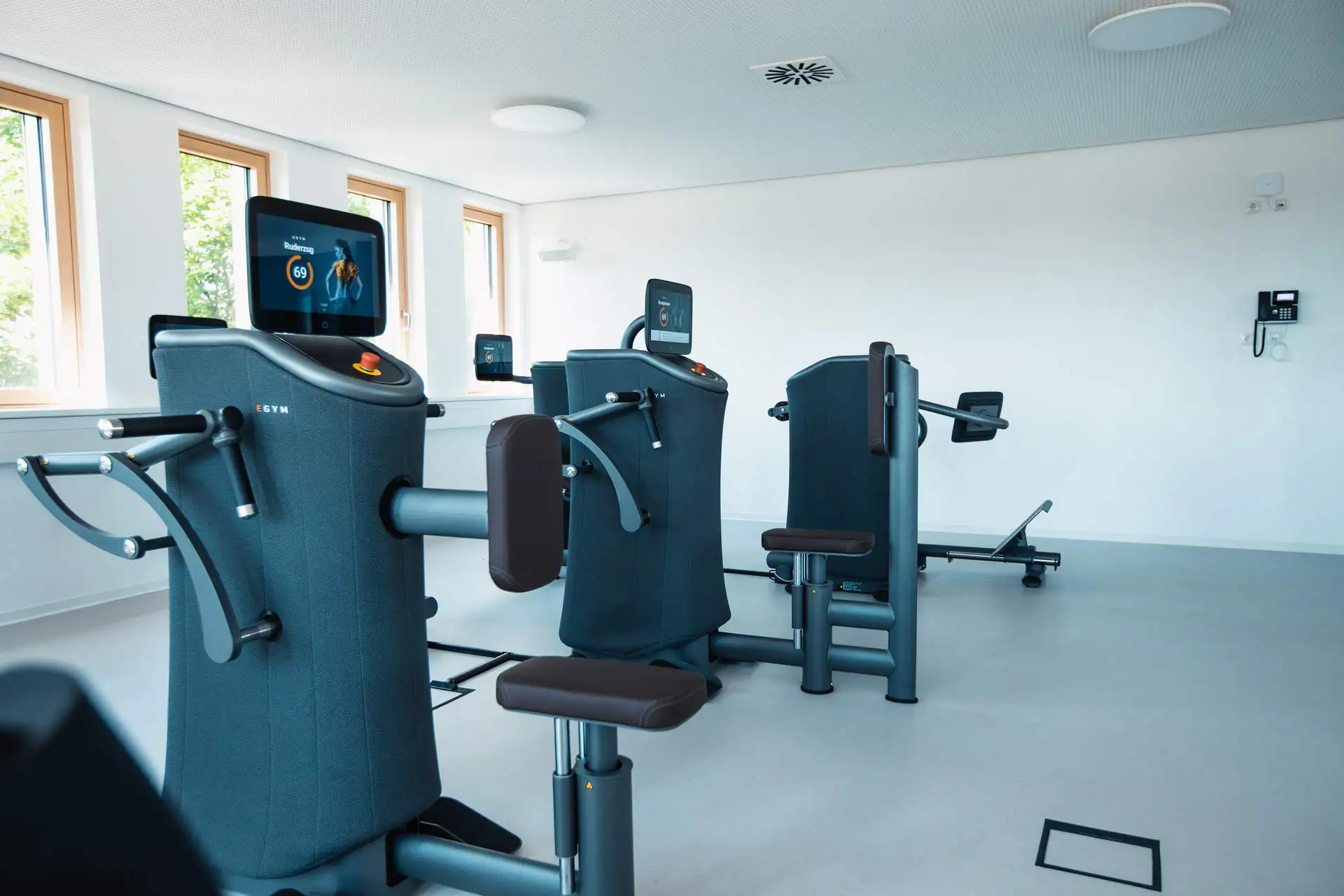 Hell erleuchteter Trainingsraum mit modernen computergestützten Fitnessgeräten, die personalisierte Trainingsdaten anzeigen.