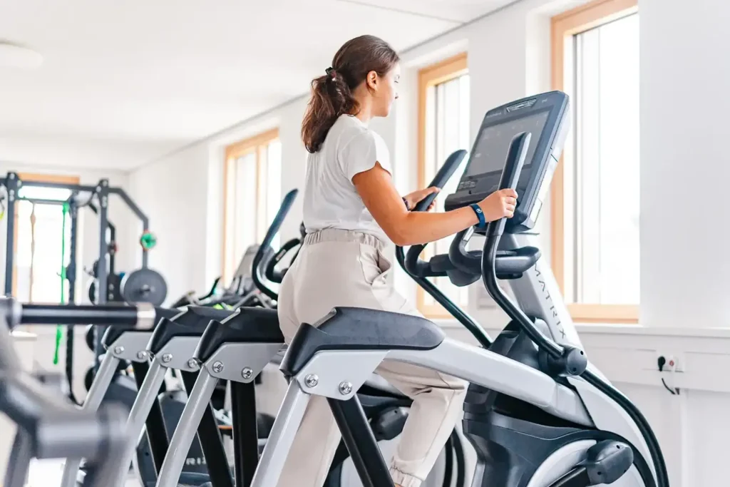 Patientin trainiert auf einem Ellipsentrainer im Rahmen der Sporttherapie in Augsburg für optimale Rehabilitation.